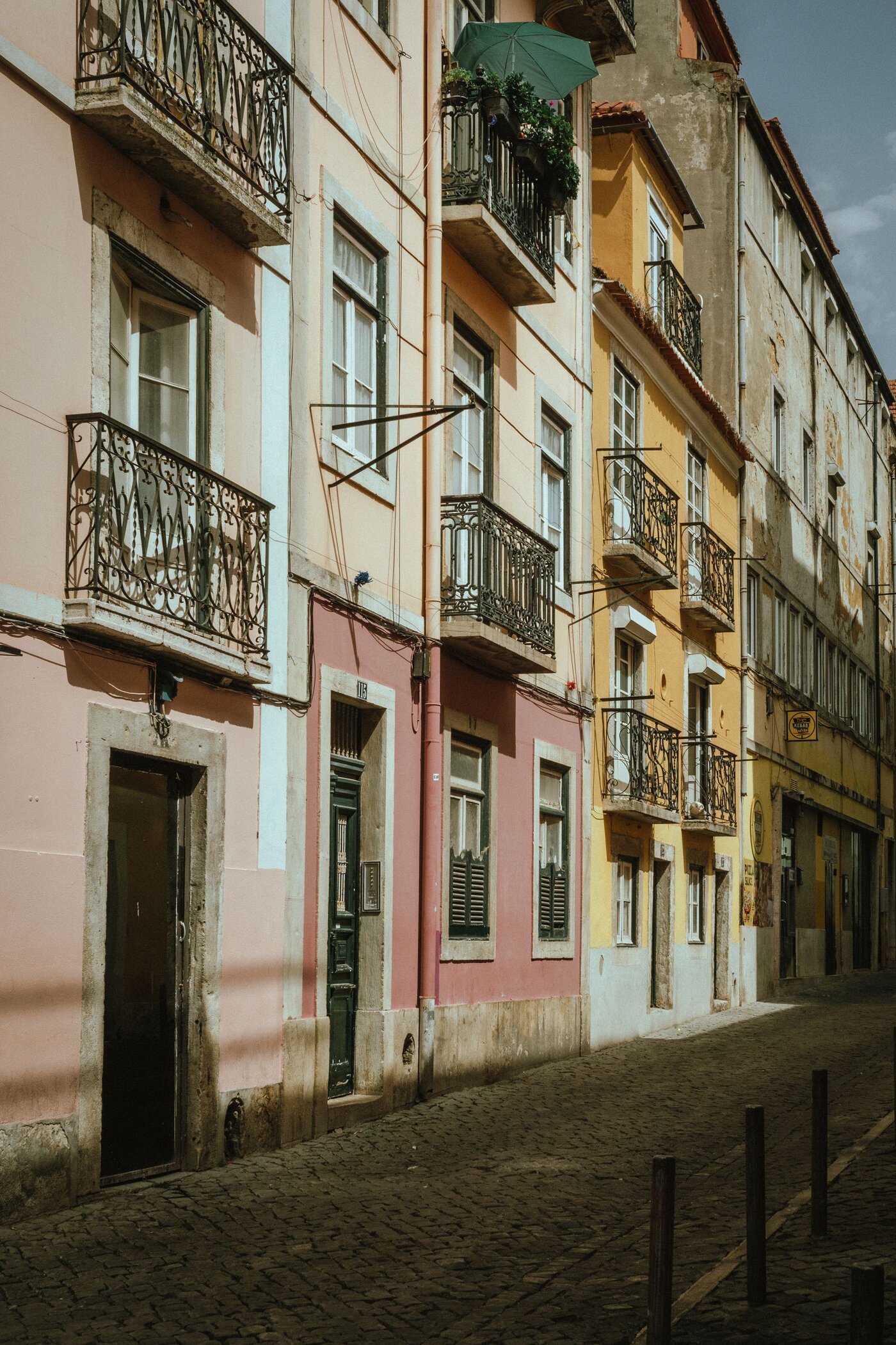 Pastel-coloured buildings and balconies along a cobbled street in Lisbon