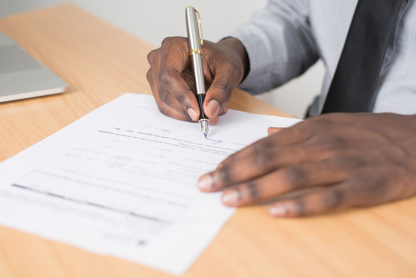 A person signing paperwork at a desk, illustrating the importance of formal transaction documents