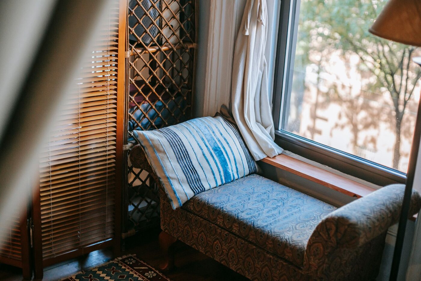 A comfortable upholstered seat beside a large window in a furnished home