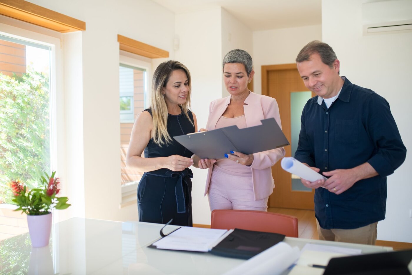 Prospective buyers reviewing property documents with an adviser during an illustrative meeting