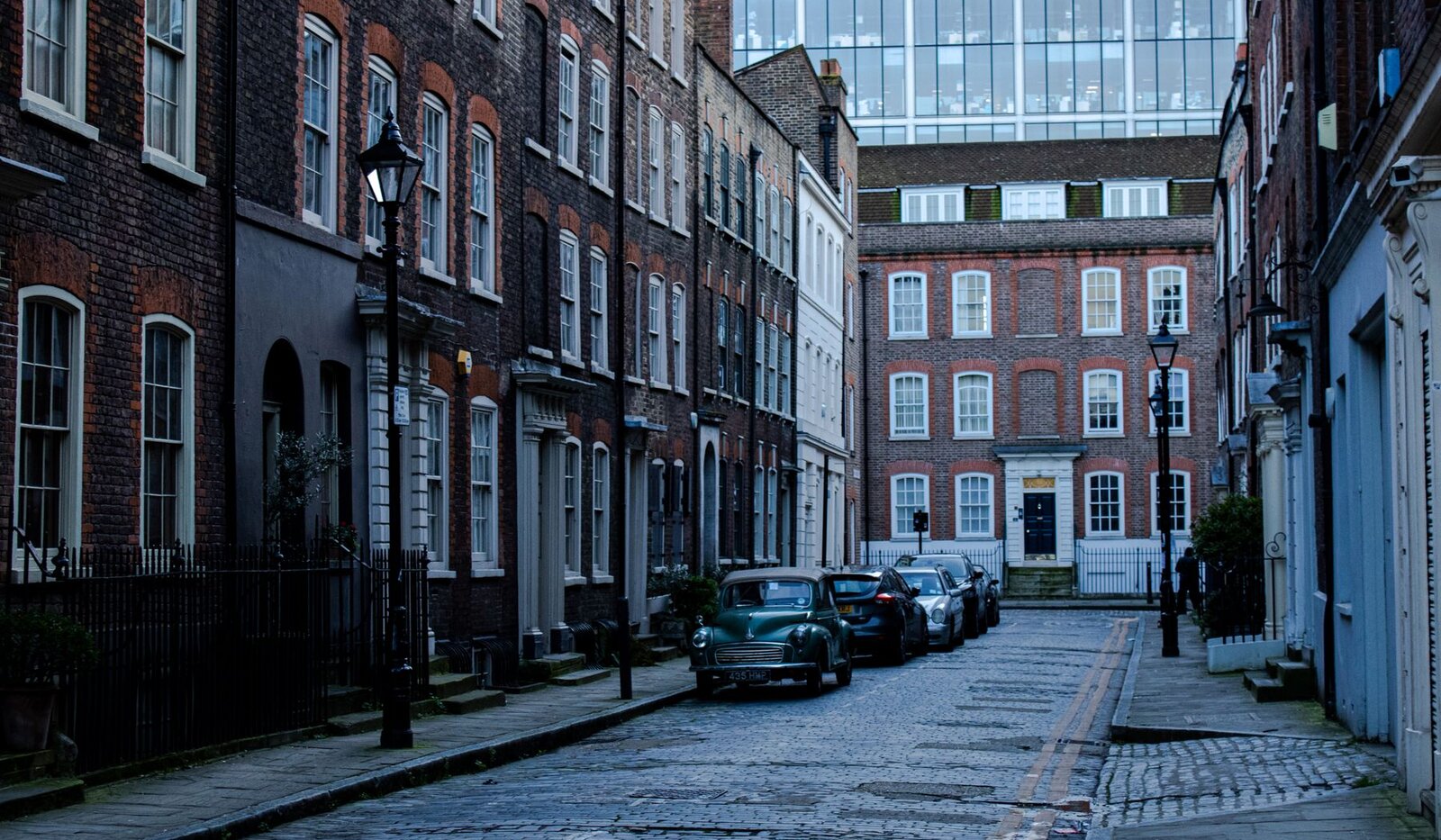 A quiet London street lined with historic brick buildings and parked cars