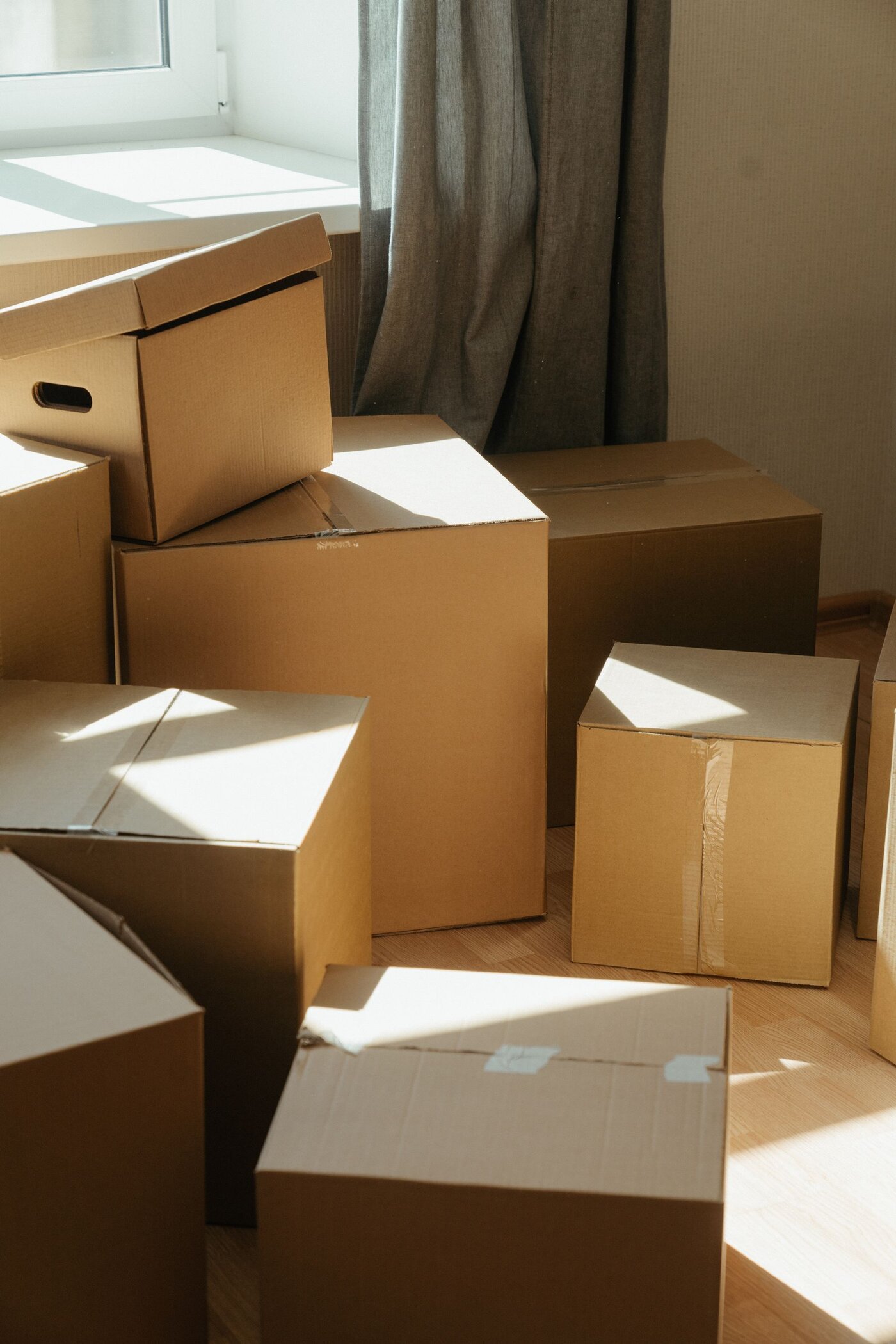 Cardboard moving boxes stacked beside a sunlit window