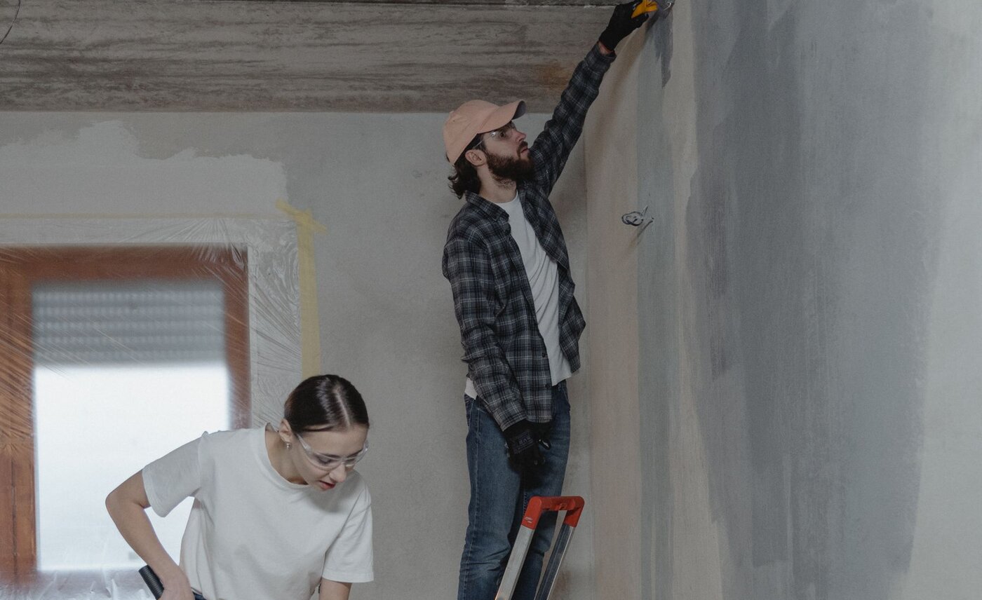 Two people preparing and painting a room during a home renovation